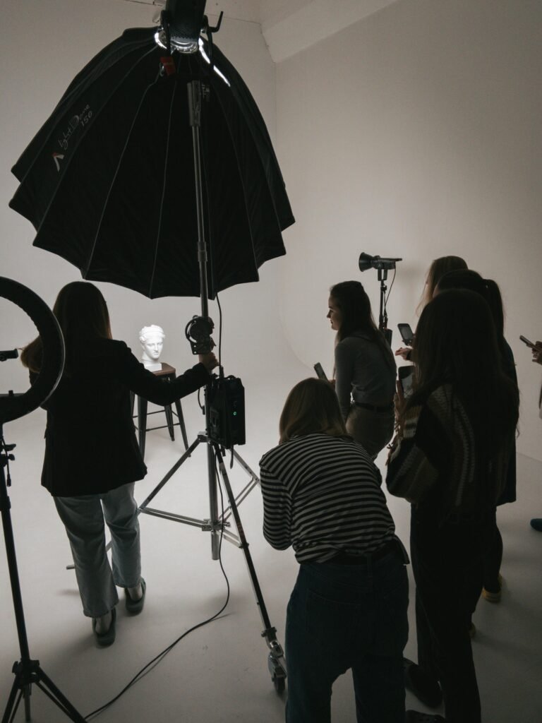 A group of photographers practices studio lighting techniques with a sculpture as the subject.